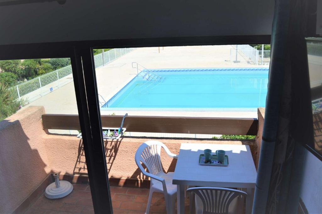 un patio avec une table et une piscine dans l'établissement Appart Studio Mezzanine 2 couchages PORT LEUCATE NATURISME PL010-832, à Port-Leucate