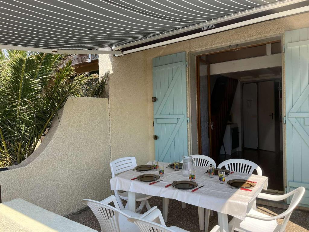 - une table blanche avec des chaises blanches sur la terrasse dans l'établissement Maison cabine mezzanine 6 couchages PORT LEUCATE NATURISME PL070-103, à Port-Leucate