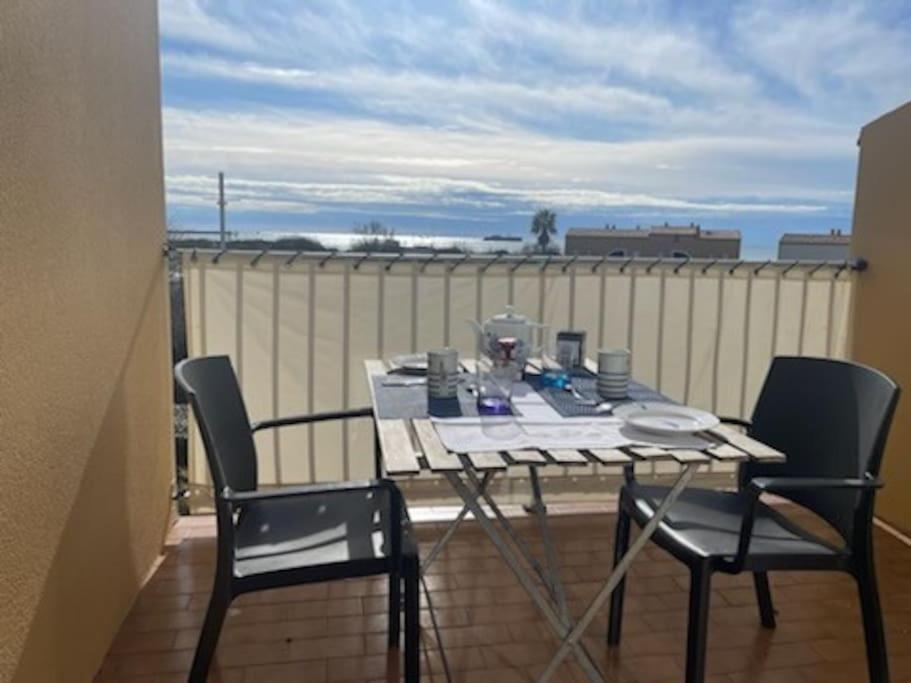 une table et des chaises sur un balcon avec vue dans l'établissement Les Terrasses de la Plage 268 , T2 climatisé, vue mer, parking, terrasse, au Cap d'Agde