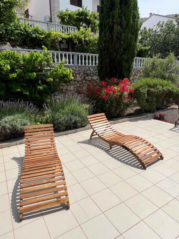 two wooden benches sitting on a patio with flowers at Apartment Ivanka in Senj