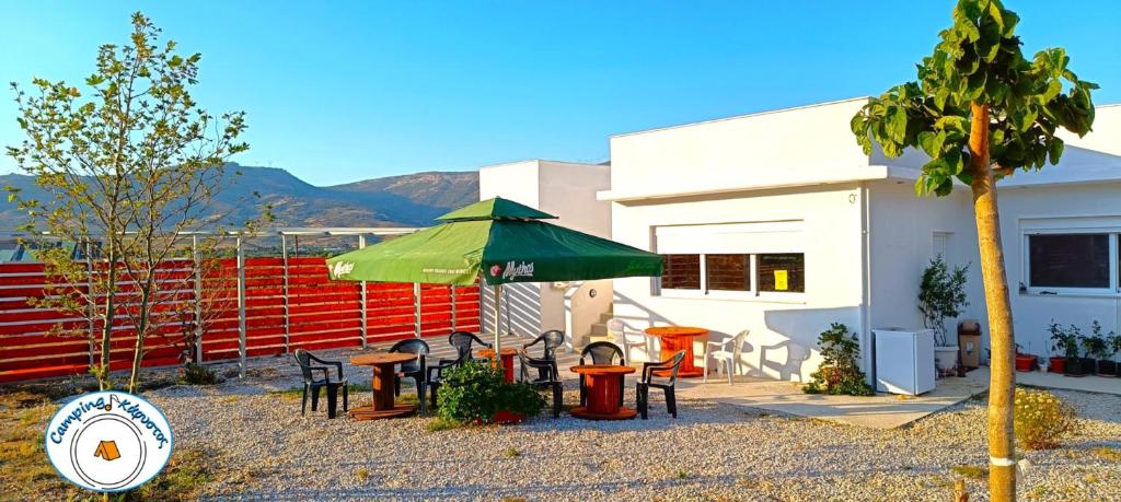 a patio with tables and chairs and a green umbrella at Camping.Karystos Melodia in Karistos