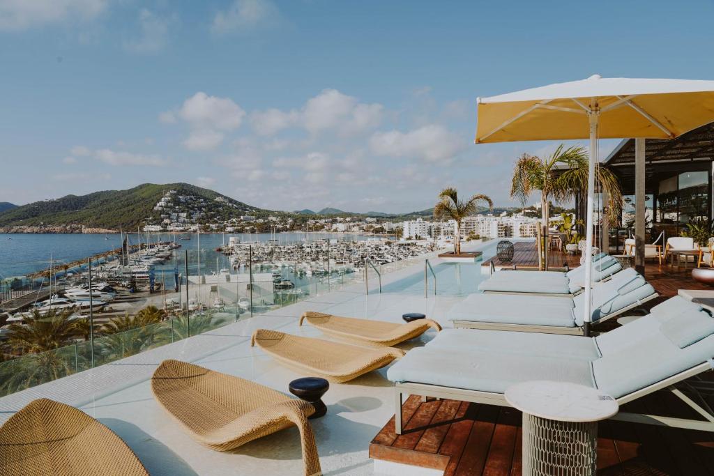 grupa krzeseł i parasoli na patio w obiekcie Aguas de Ibiza Grand Luxe Hotel - Small Luxury Hotel of the World w mieście Santa Eularia des Riu
