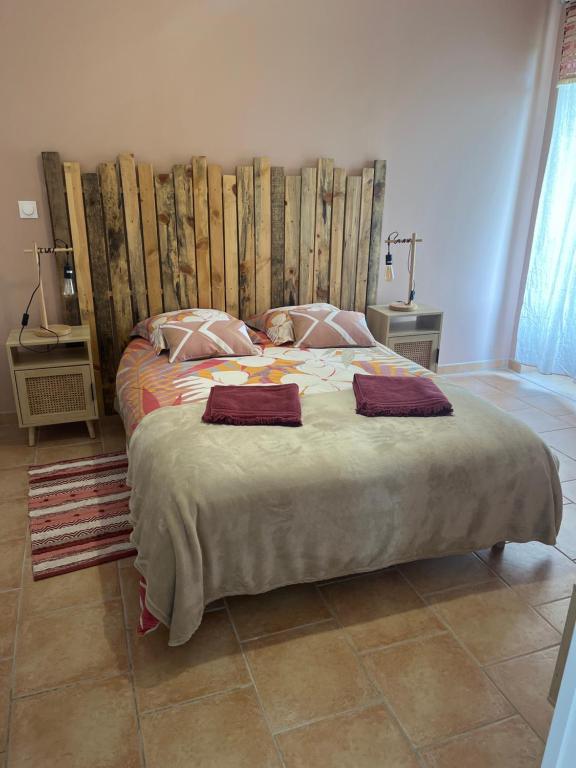 a bedroom with a large bed with a wooden headboard at Chez Marjo & Flo in Gageac-et-Rouillac