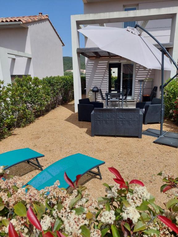 d'une terrasse avec 2 tables et un parasol blanc. dans l'établissement VILLA DE BELGODERE LOZARI, à Belgodère