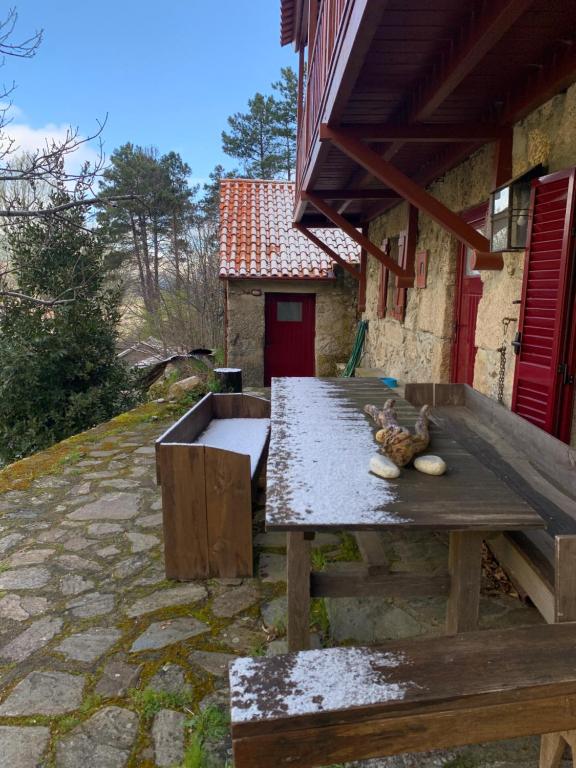 a wooden picnic table in front of a building at Chalé na Montanha Casa de Baixo in Manteigas
