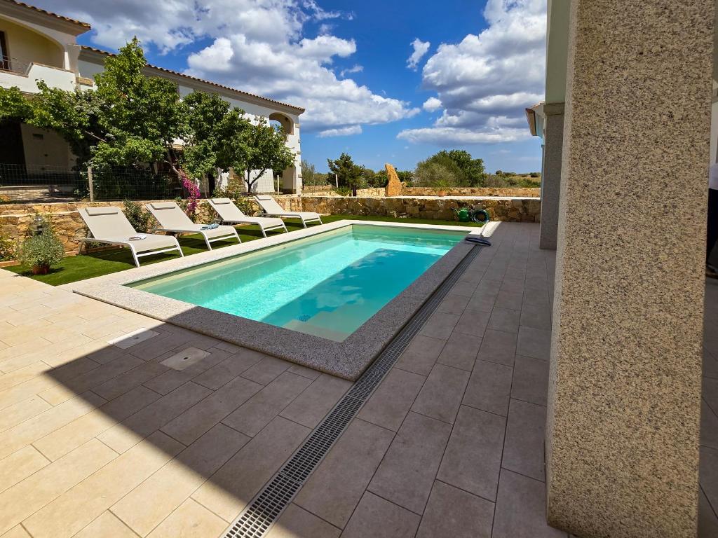 a swimming pool in a yard with chairs and a house at La Casa di Emy in Budoni
