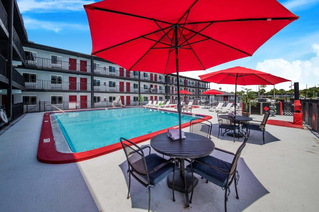 a pool with tables and chairs and a red umbrella at Seasons Florida Resort in Kissimmee