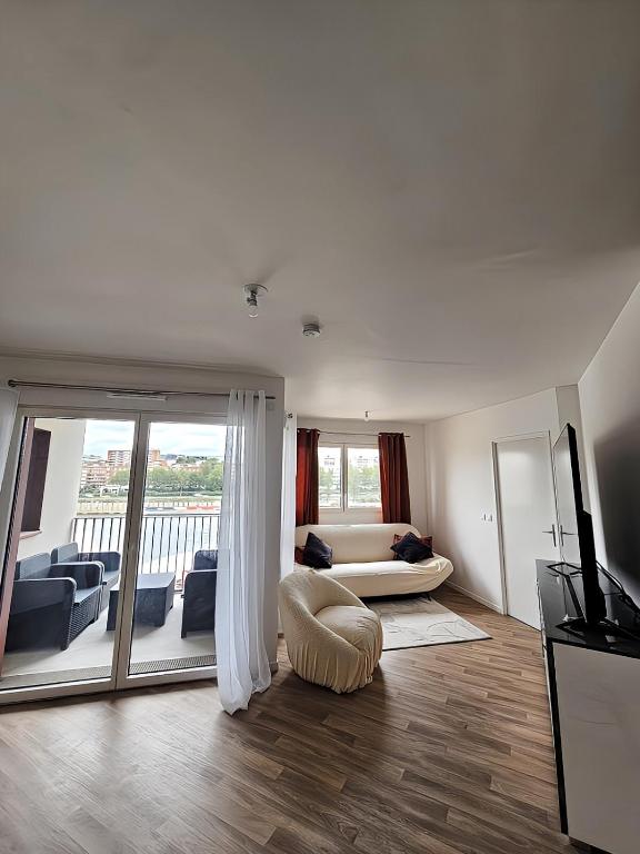 d'un salon avec un canapé et un balcon. dans l'établissement F4 avec Terrasse & Vue sur Seine 10 min de Paris, à Ivry-sur-Seine