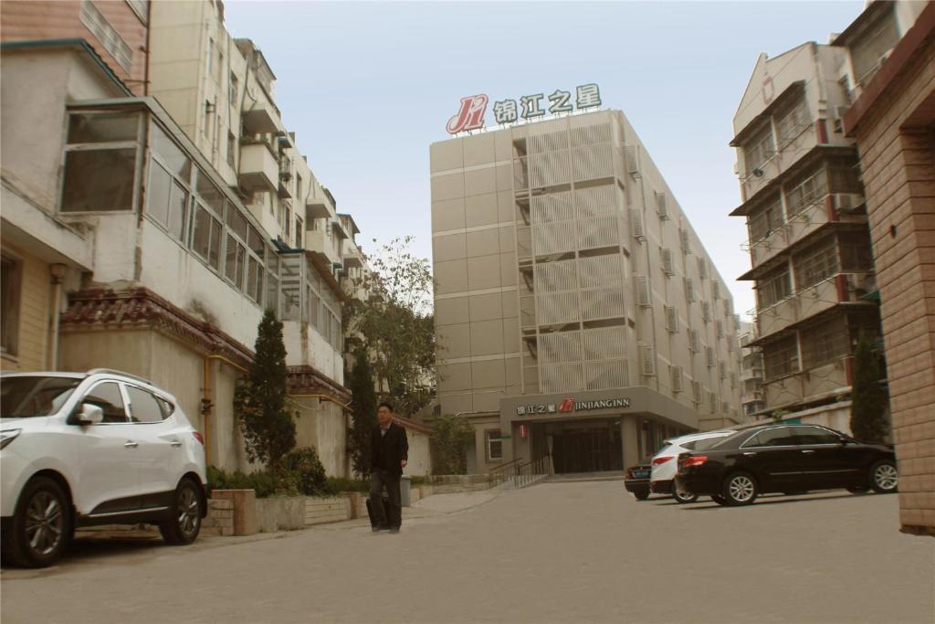 Ein Mann steht auf einer Straße vor einem Gebäude in der Unterkunft Jinjiang Inn Bengbu Railway Station First Jiefang Road in Bengbu