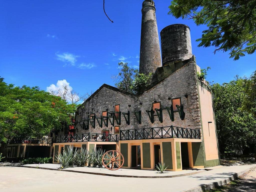 a building with a chimney with a wagon in front of it at Hacienda San Francisco Tzacalha in Dzidzantún