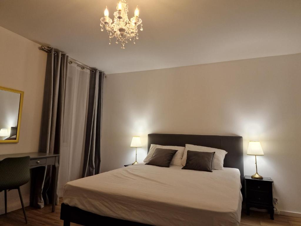 a bedroom with a bed and a chandelier at Superbe Appartement très lumineux in Concarneau