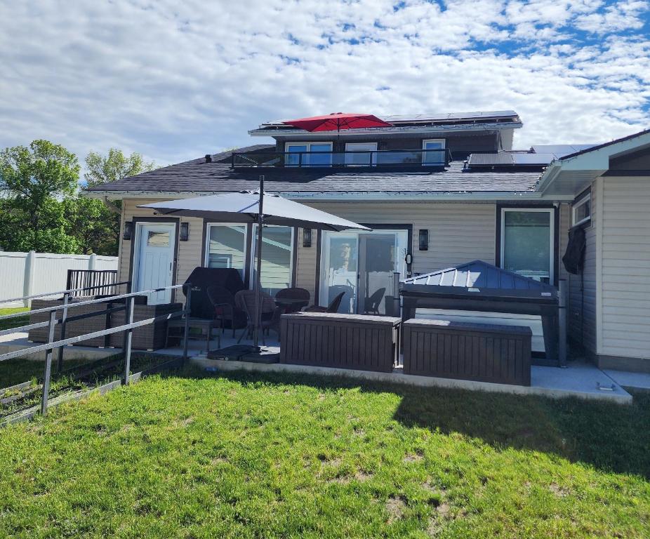 a house with a patio with an umbrella and chairs at Loft with Patio & Hot tub in Lethbridge