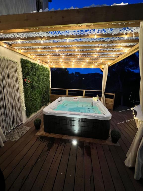 a hot tub on a deck with lights at LOVE ROOM Tente Lodge spa MFG chez C&C, exclusivement réservée aux ADULTES in Cantaron