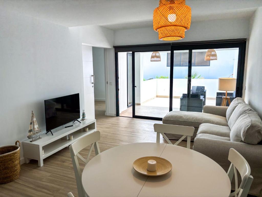 a living room with a couch and a table and a tv at Infinito in La Oliva