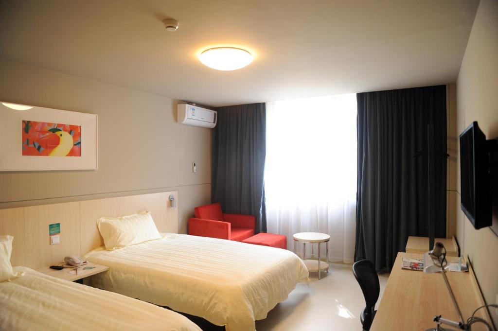 a hotel room with a bed and a red chair at Jinjiang Inn Shangrao Zhongshan Road in Shangrao