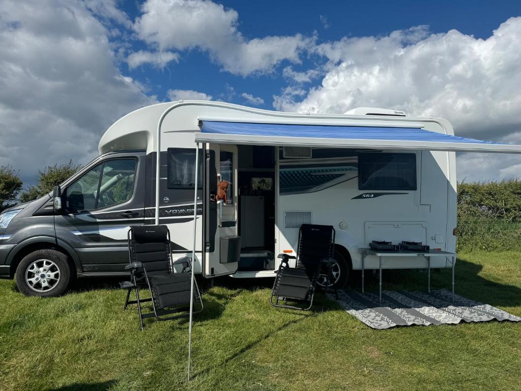 Una autocaravana con un toldo azul estacionada en un campo en Motorhome life, en Radipole