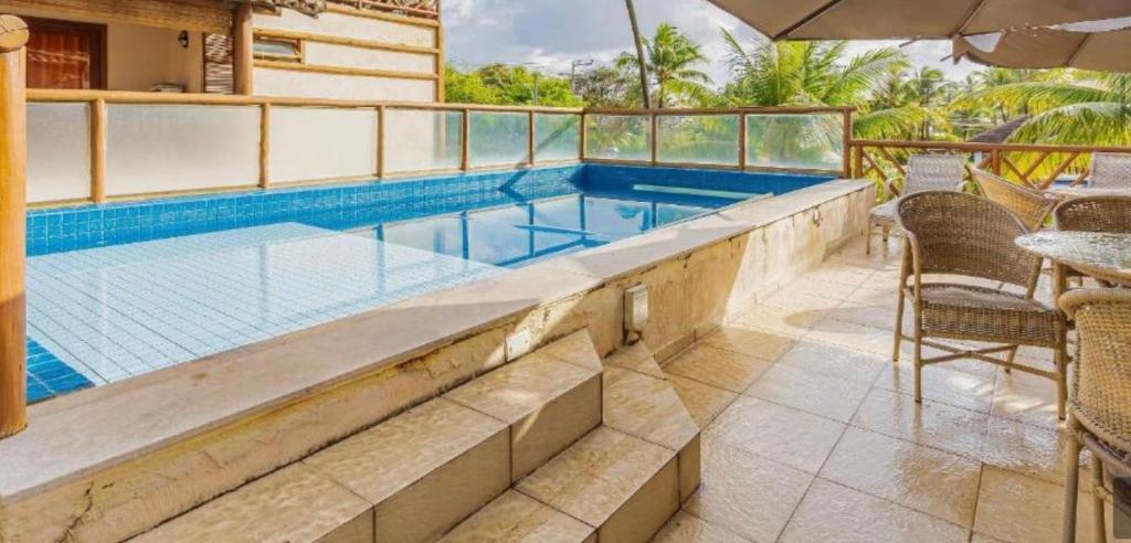 a swimming pool with a table and chairs on a patio at Moderno 1 Quarto Dentro da Vila in Praia do Forte