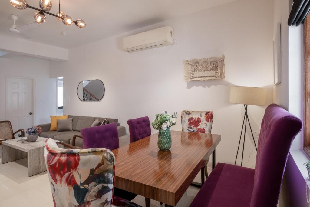 uma sala de estar com uma mesa de madeira e cadeiras roxas em Staymaster Amber Avenue I 3BR em Verla
