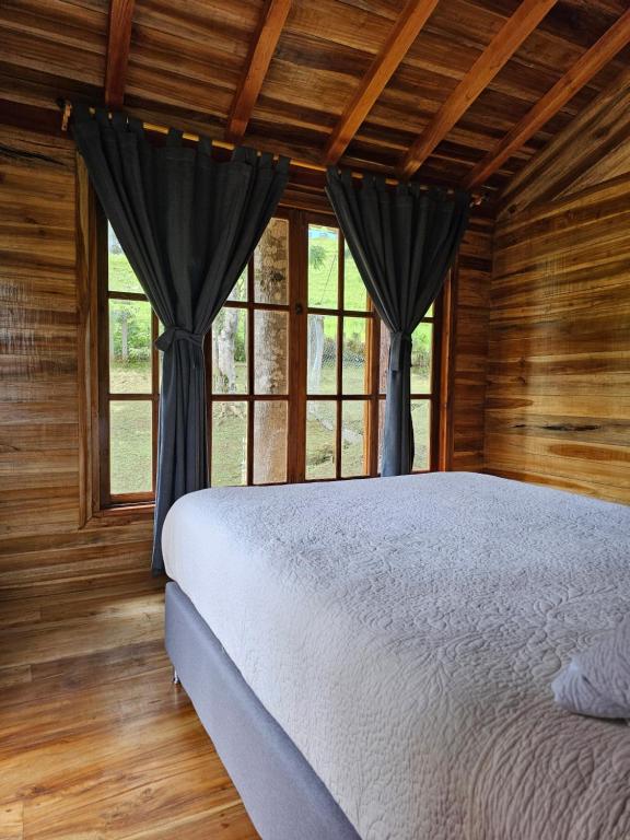 Un dormitorio con una cama en una habitación con ventanas. en Cattaleya Eco, en Yumbo