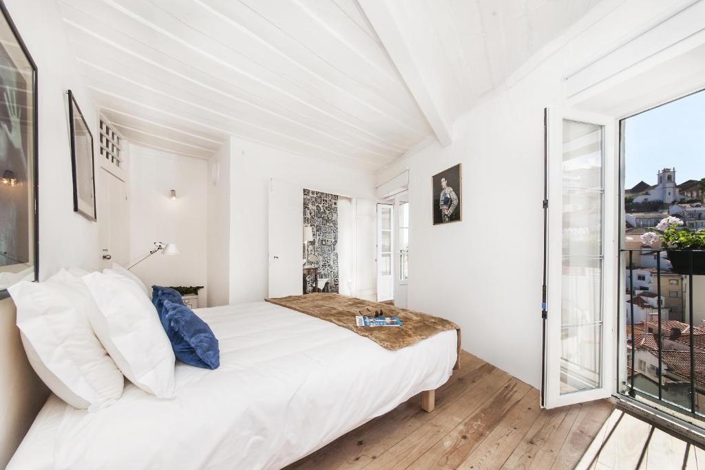 a white bedroom with a bed and a large window at Alfama - St Estevão viewpoint | Lisbon Cheese & Wine Apartments in Lisbon