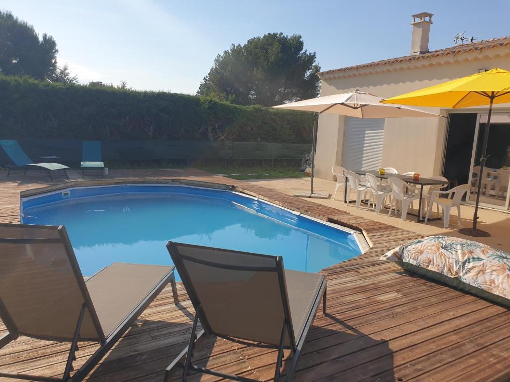 - une piscine avec des chaises, une table et un parasol dans l'établissement maison provence, à Mazan