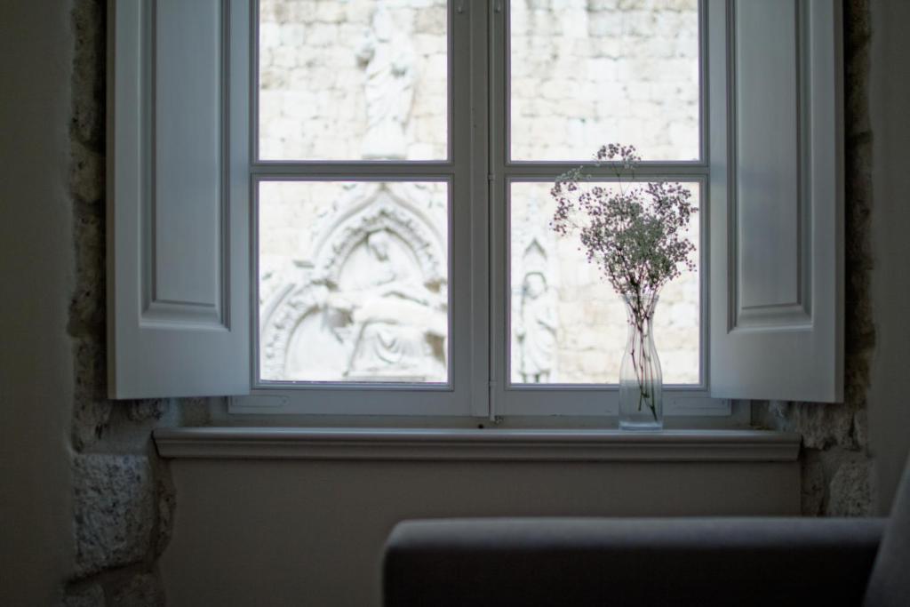 a window with a vase with flowers in it at Apartments Eleganca, crypto payment accepted in Dubrovnik