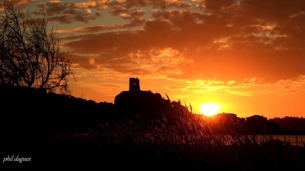 a sunset with a silhouette of a building on a hill at Location Nuit Studio Port Gruissan in Gruissan