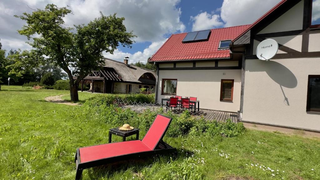 a red chair and a table in front of a house at Pērles in Durbe