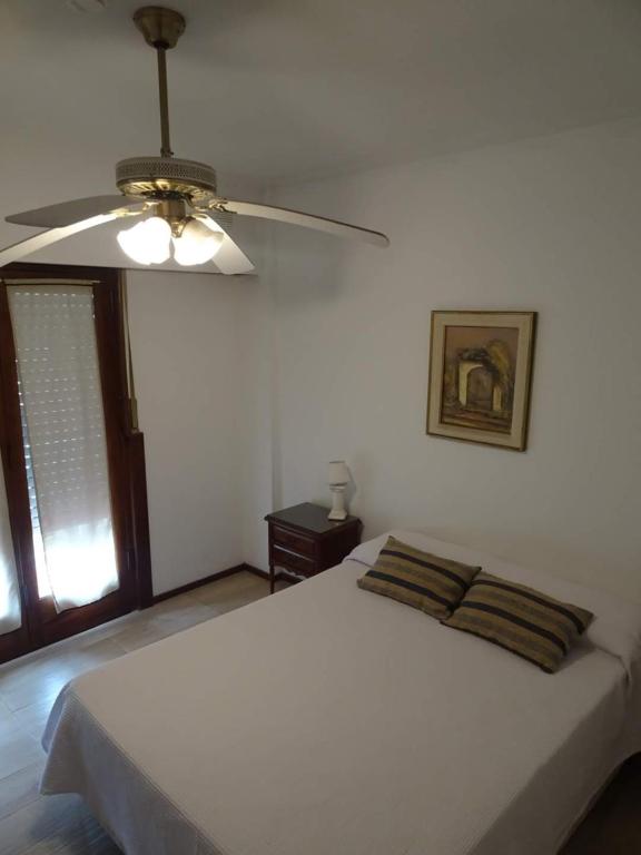 a bedroom with a white bed with a ceiling fan at Hotel Hispania Miramar in Miramar