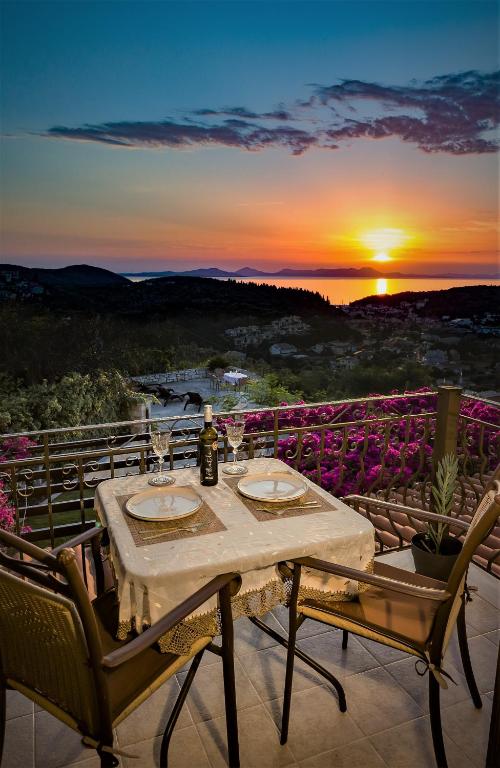 a table and chairs on a balcony with a sunset at Sivota Royal in Syvota