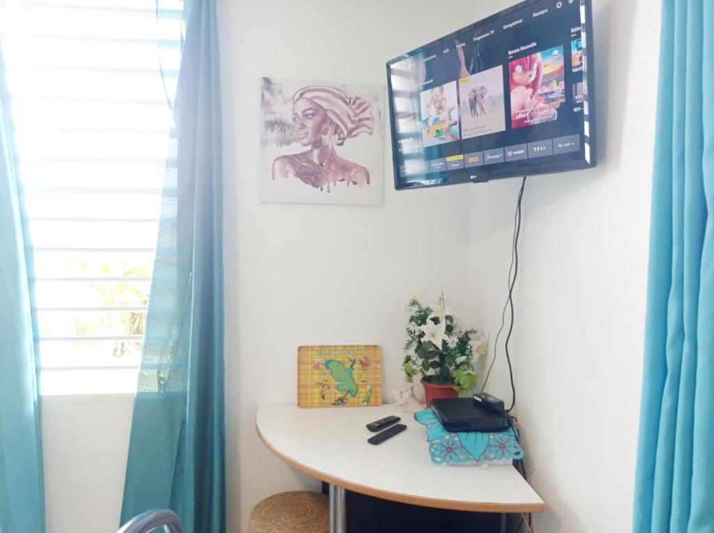 una camera con tavolo e TV a parete di Chambre d'hôte Kay Arlette - chez l'habitant a Le Robert