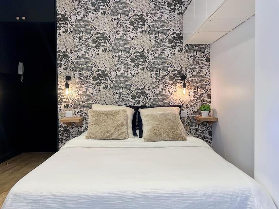 - une chambre avec un lit blanc et du papier peint noir et blanc dans l'établissement Fully renovated studio for 2, à Paris