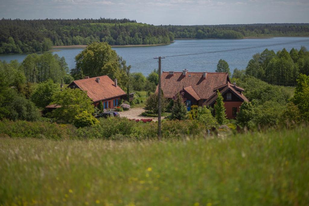 two houses on a hill next to a lake at Lipowy dom in Piecki