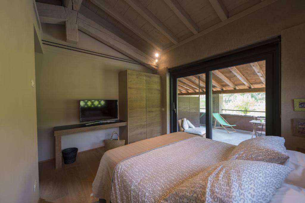 a bedroom with a bed and a tv and a balcony at Agriturismo Locanda Del Pesco in Collebeato 