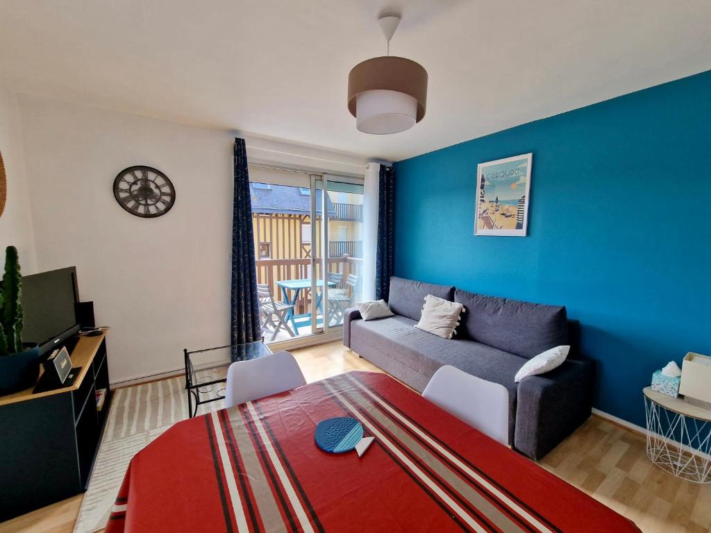 un salon avec un canapé et un mur bleu dans l'établissement Côté Plage & Balcon, à Cabourg