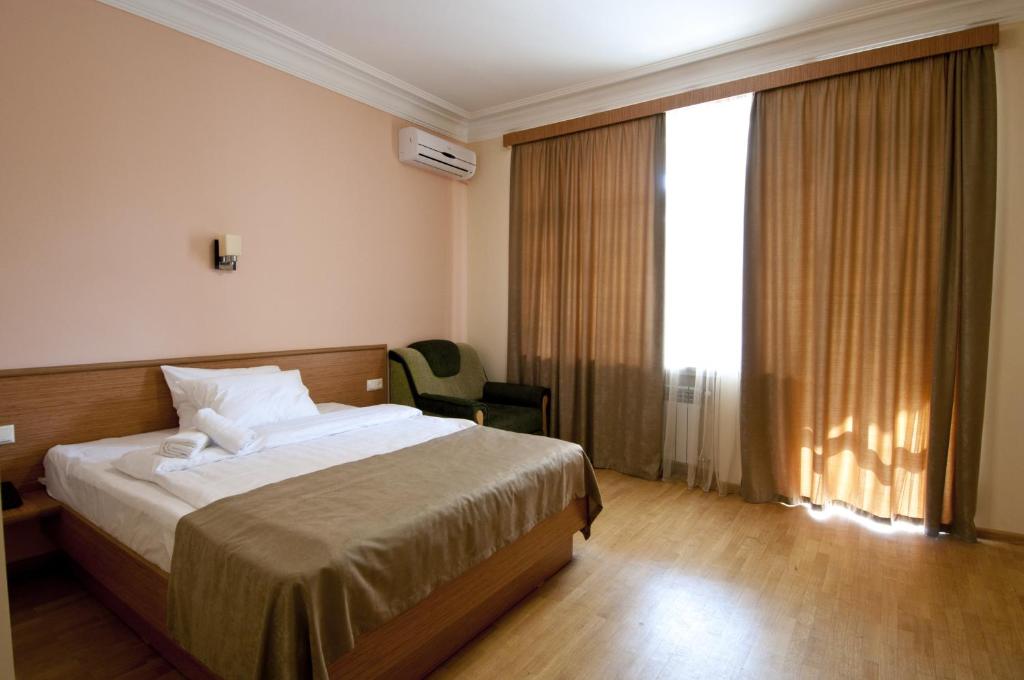 een hotelkamer met een bed en een groot raam bij Albert House Hotel and Tours in Jerevan