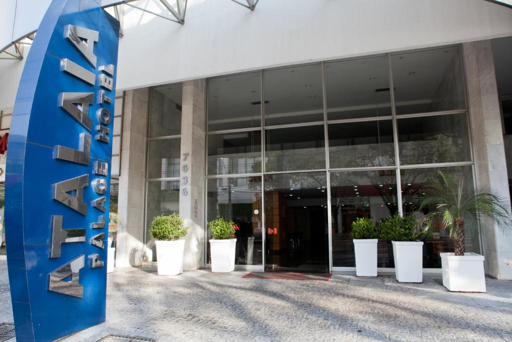 um edifício com vasos de plantas à sua frente em Atalaia Palace Hotel em Guarapuava