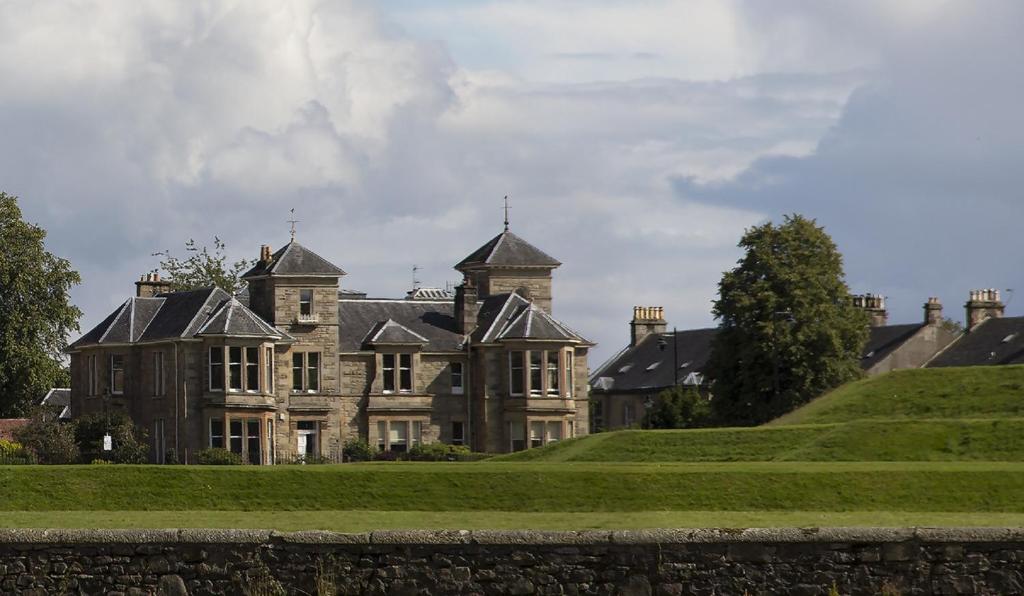 una casa vieja en una colina con césped verde en Royal Gardens Apartments, en Stirling