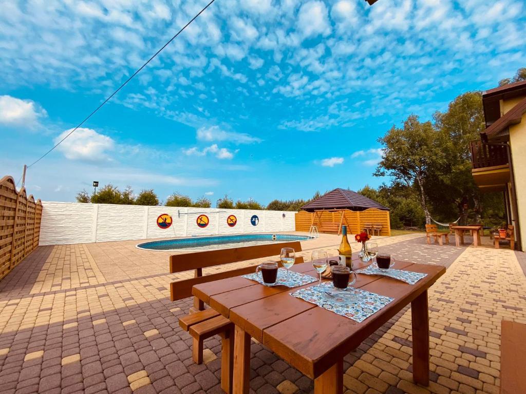 a patio with a wooden table and a swimming pool at Ptasi Raj in Karwia