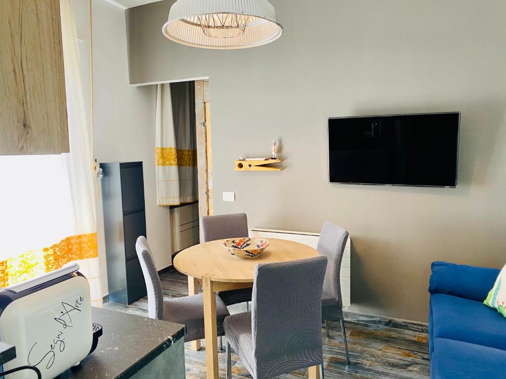 een woonkamer met een tafel en stoelen en een televisie bij S'accabbadora Guest House in Alghero