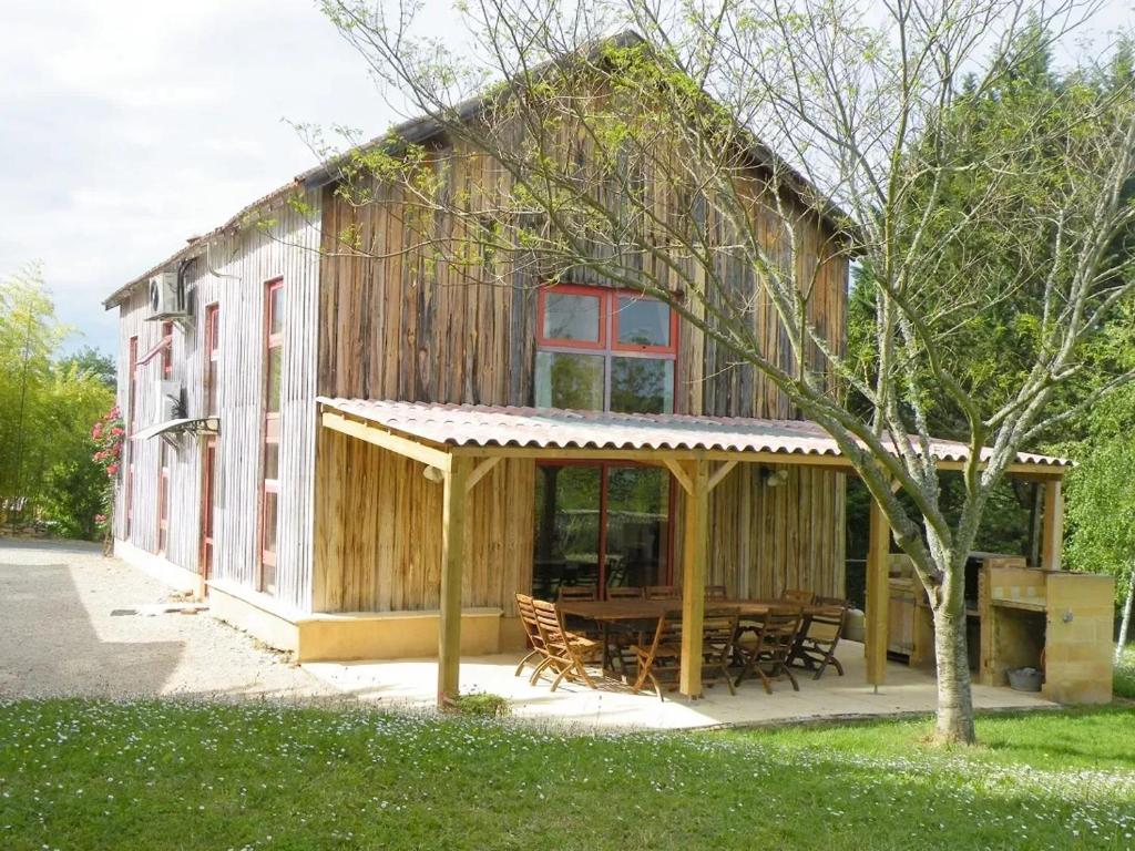 une maison en bois avec une table de pique-nique devant elle dans l'établissement Maison familiale avec piscine privée à Le Buisson-de-Cadouin, au Buisson de Cadouin