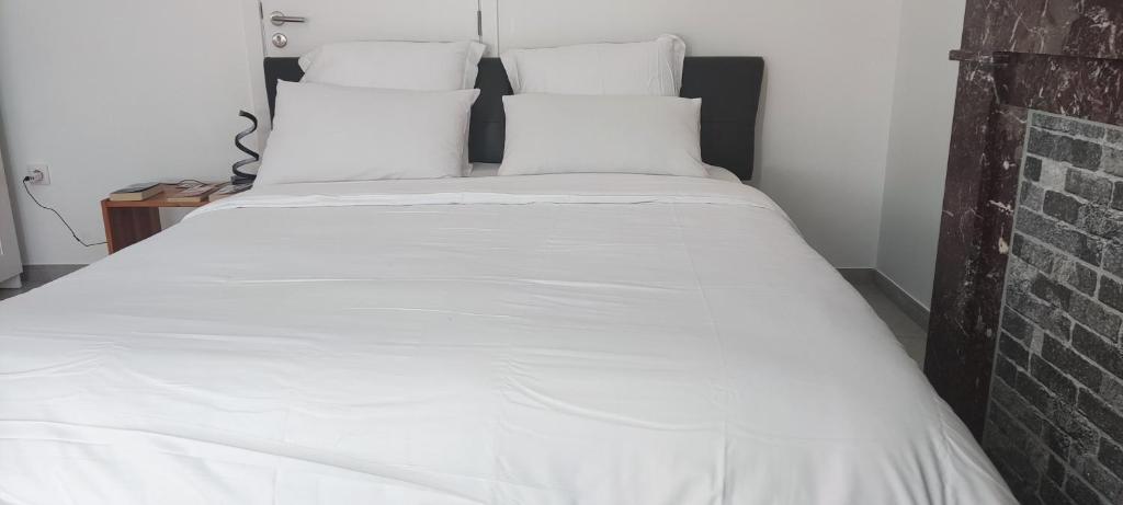 a large white bed with white sheets and pillows at Chambre R0 avec salle de bain partagée près de l'hôpital de la Citadelle à Liège in Liège