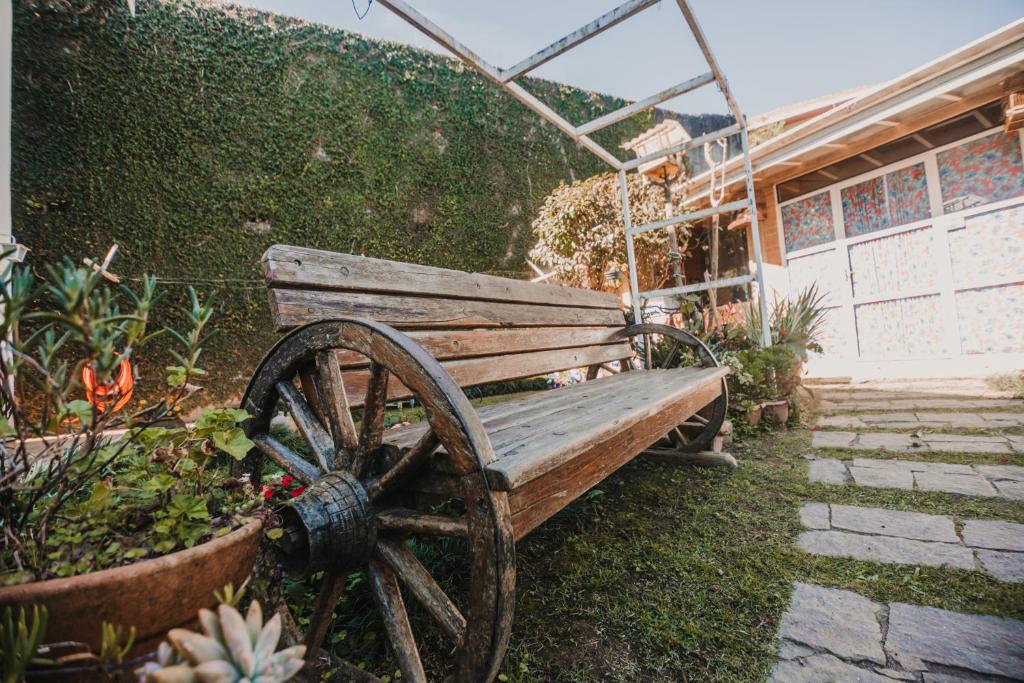 a wooden bench sitting next to a garden at Portal Flores Suítes in Campos do Jordão