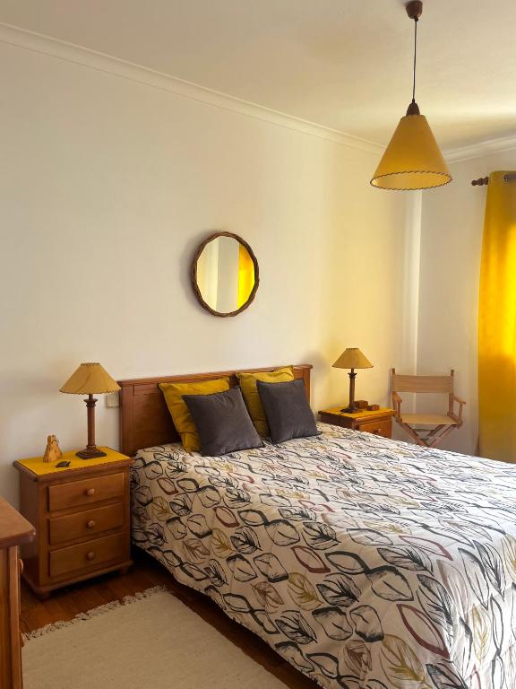 a bedroom with a bed with two lamps and a mirror at Casinha das Memórias in Vieira de Leiria