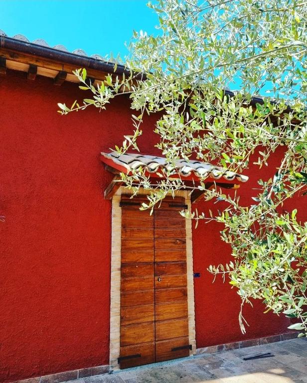 a red building with a wooden garage door at Terre di Cornossa in Marta