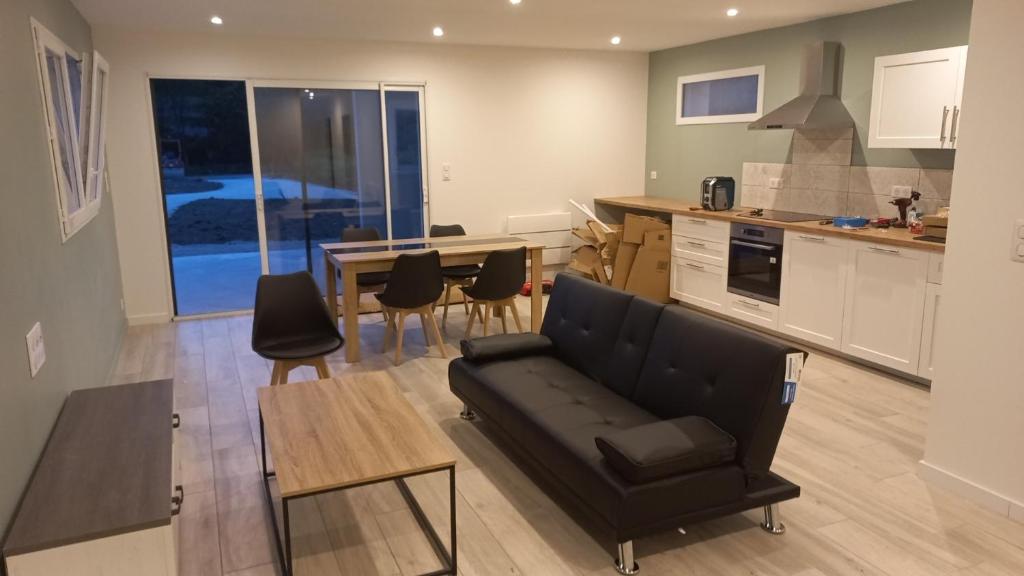 un salon avec un canapé et une table et une cuisine dans l'établissement La maison du menhir, à Crozon