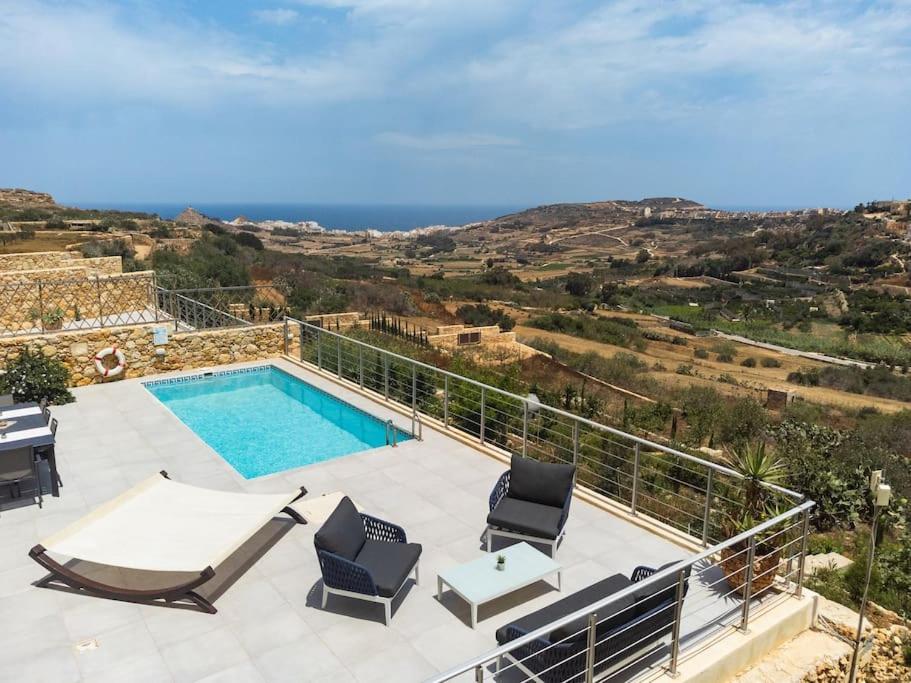 a villa with a swimming pool and a view of the ocean at Clifftop Lodge in Tal-Barmil