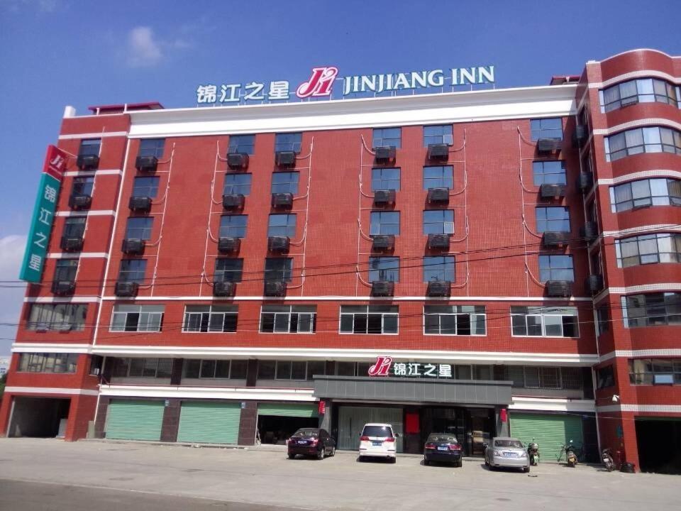 un bâtiment rouge avec des voitures garées dans un parking dans l'établissement Jinjiang Inn Xiamen Xiang'an Maxiang, à Xiamen