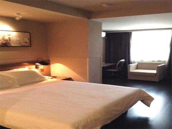 a hotel room with a large bed and a chair at Jinjiang Inn Shenyang Middle Street Pedestrain in Shenyang