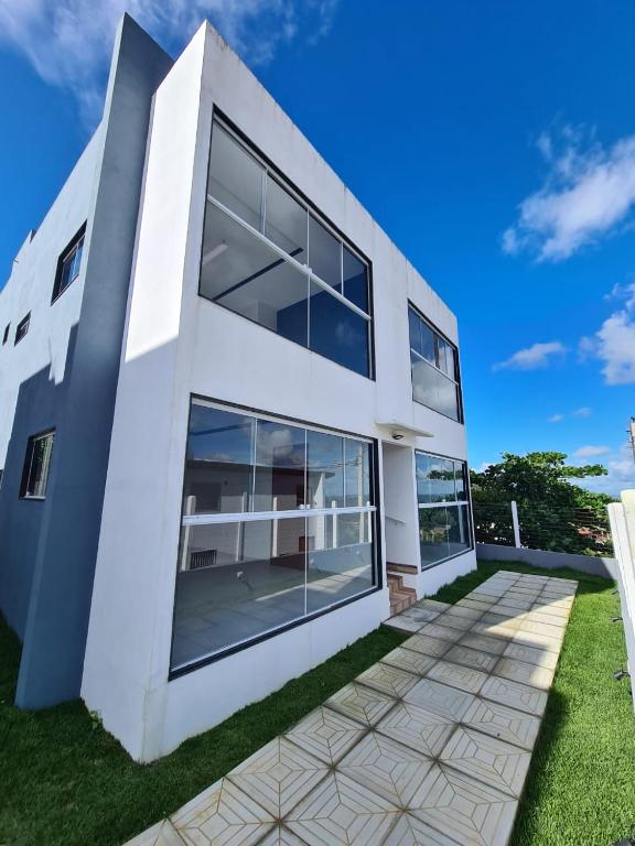 a white house with glass windows on a lawn at Apartamento Vale da Lua, Bezerros in Bezerros